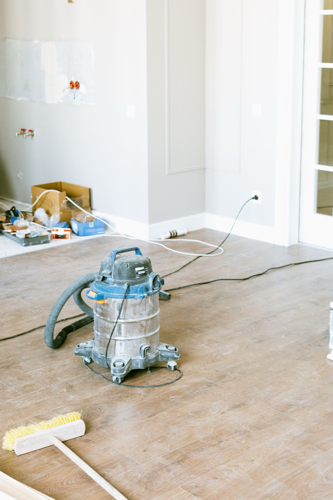 Aspirateur de chantier et balai dans une pièce en rénovation